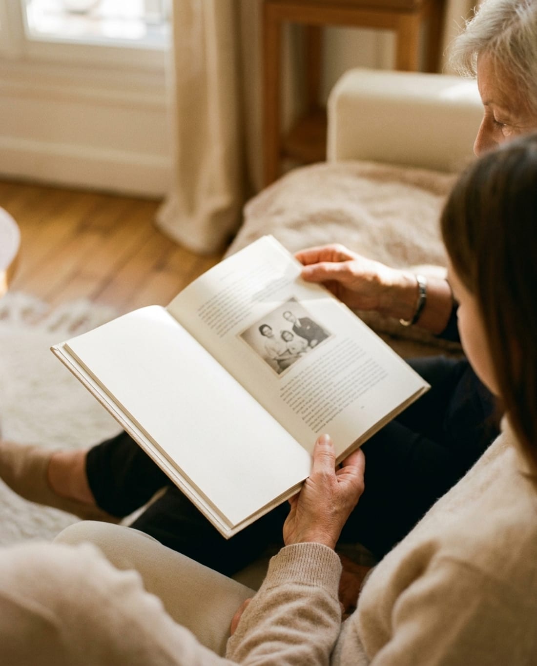 Une grand-mère et sa petite-fille regardent ensemble le livre ouvert, une photo de famille imprimée dans la page